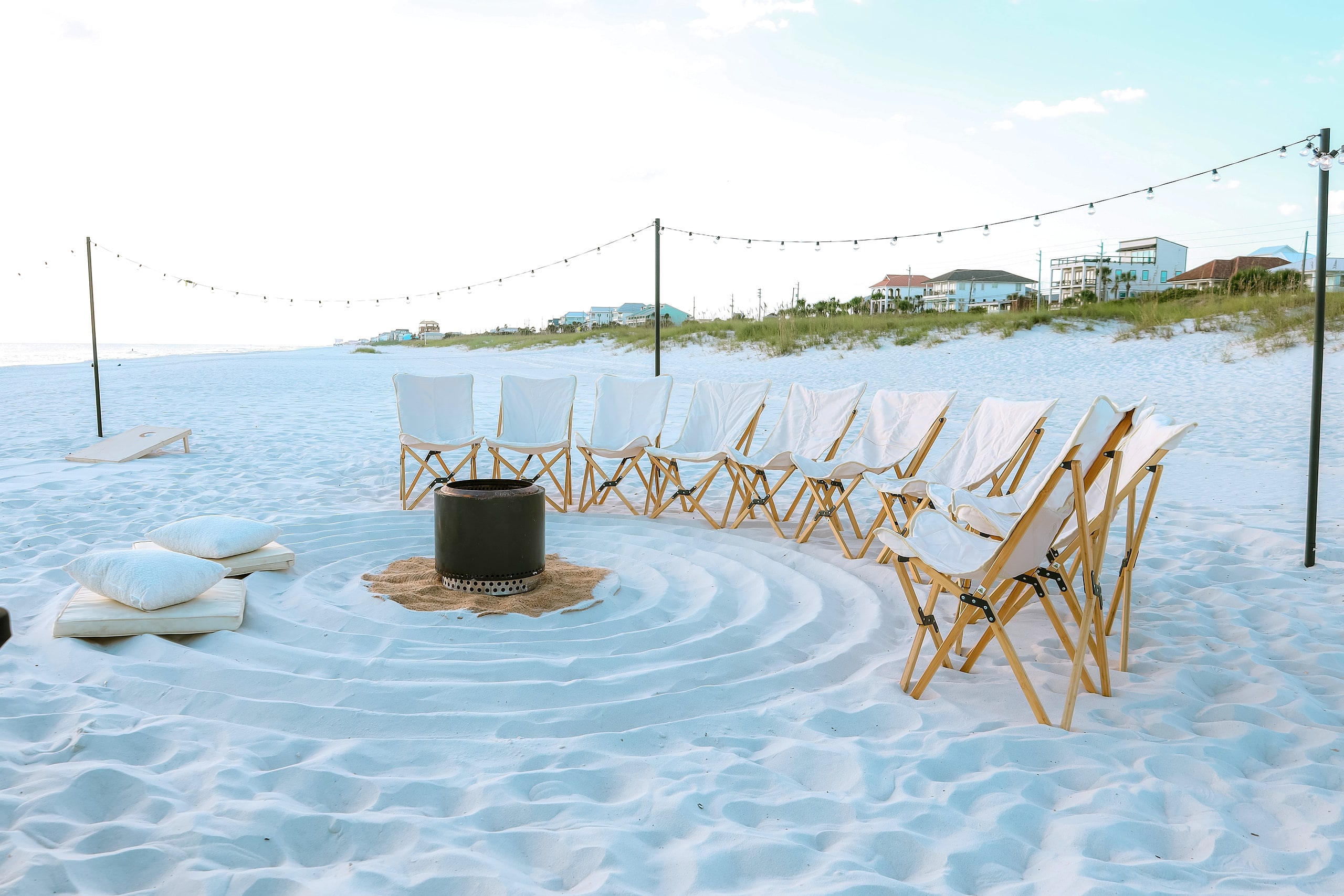Wide styled beach bonfire setup with lawn games and string lights
