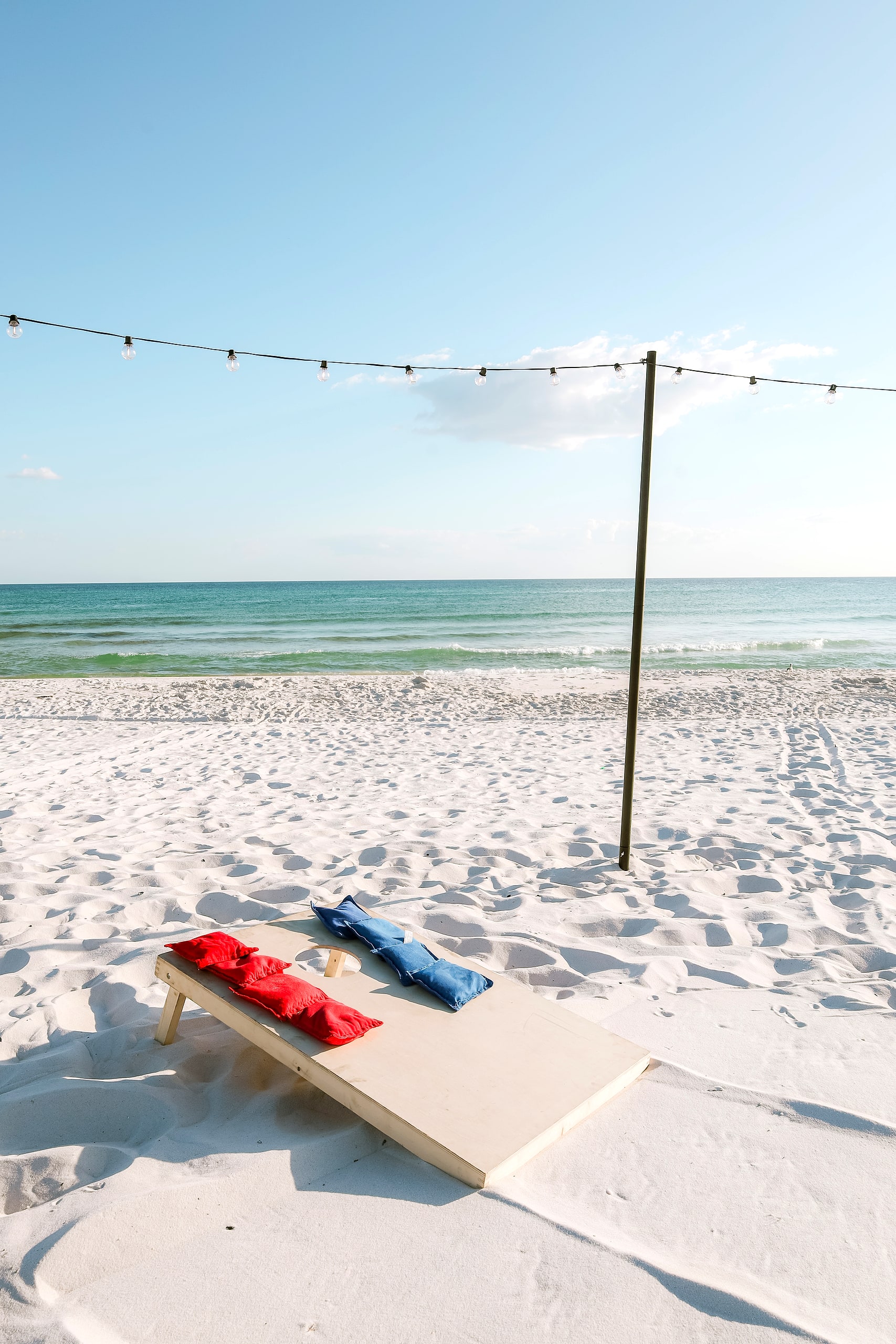 Cornhole set up on the white sand by the Gulf